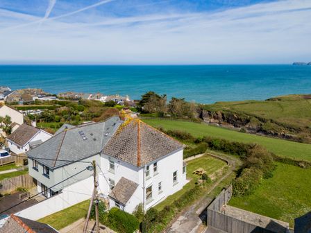 A coastal landscape with houses green fields and the sea in the background at Tamarama House in Port Isaac