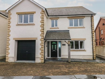 A two-story house with a black garage door and black front door at Llygad Y Lleuad Moon in Burry Port