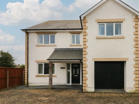 A two-story house with white exterior walls a black front door and a garage door in Burry Port