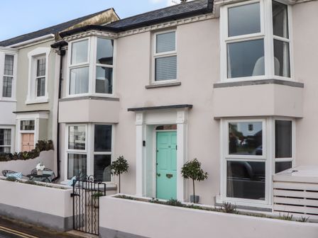 A residential street view showing two attached houses with bay windows and pastel-colored front doors at Sanctuary Cottage in Shaldon