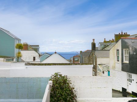 Rooftops and houses with a view of the sea under a blue sky at Whitecaps in St Ives