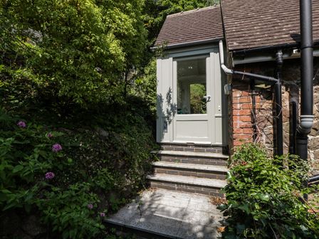 A stairway leading to a glass door on a brick and stone house surrounded by dense greenery and plants at Amazing View in Malvern