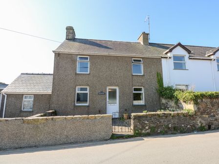 A two-story stone house with a small gate and stone wall in front at 2 Bryn Hyfryd in Abersoch