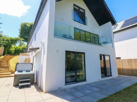 The exterior of a modern two-story house with glass balcony and patio at Valise in Bideford