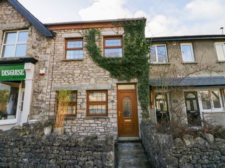 Stone fronted house with wooden door and windows next to a barber shop at Time and Tide in Arnside
