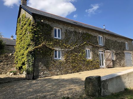 Stone house with ivy on the walls and gravel driveway at Dishcombe Cottage in Sticklepath