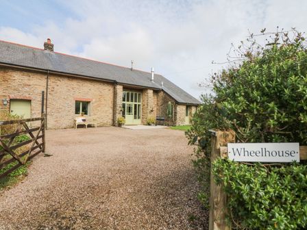 An exterior view of a stone house with a gravel driveway and a wooden gate at Wheelhouse in Muddiford near West Down