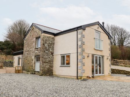 A two story house with stone and plaster walls and gravel driveway at La Petit Maison in St Columb Major
