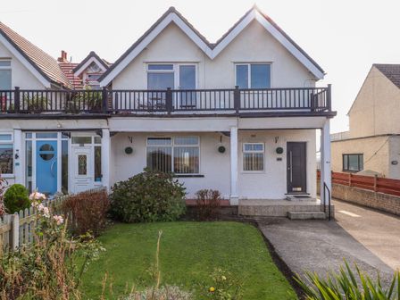 A semi detached house with a balcony a garden and a driveway at Seaward in Rhos On Sea