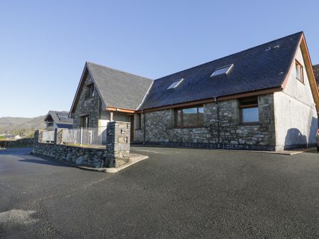 A stone house with a slate roof and large driveway at Y Tylwyth in Blaenau Ffestiniog