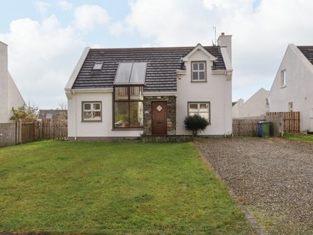 A house with a tiled roof a large front window and a gravel driveway at Sea Spray Cottage in Rathmullan County Donegal