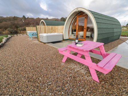 A pod with green roof near wooden pink and blue picnic tables and a hot tub at The Wheelhouse Pod No 3 in Burtonport County Donegal