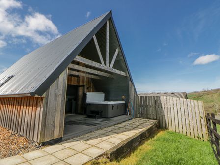 An outdoor area with a hot tub and wooden fences at Valley View Hideaway in Ffostrasol