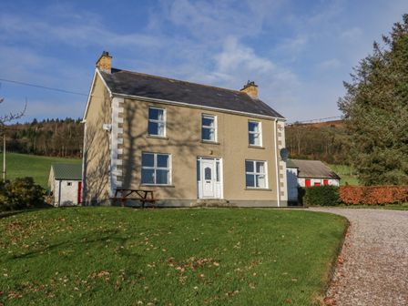 A two story house with a grassy lawn and a gravel driveway at Alcorns Farmhouse in Glencross near Rathmullan