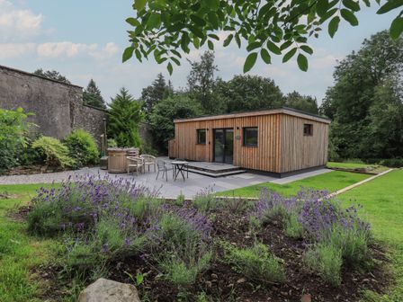 A wooden garden building with outdoor seating and lavender plants at The Gardener's Retreat in Hutton John near Penruddock