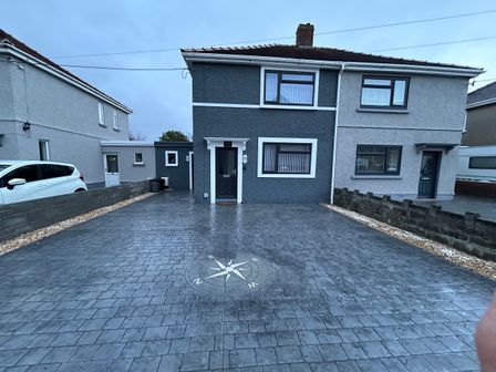 A semi detached house with a large driveway and compass design on the pavement at Swn Y Mor in Burry Port
