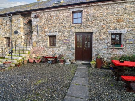 An outdoor stone patio area with a wooden door stone stairs metal chairs and tables and potted plants at The Abraham in Castledermot County Kildare