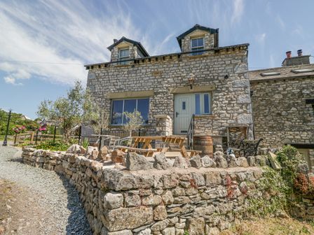 A house with stone walls and patio furniture at Old Watermill in Cartmel