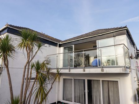 The exterior of a two-story house with glass balcony and palm trees at 36 Coedrath Park Saundersfoot