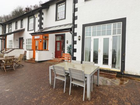 An outdoor patio area with tables and chairs in front of a white building at 5 Ladstock Hall in Thornthwaite near Keswick