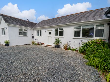 A white house with gravel driveway and plants around the entrance at Polwen Harlyn Bay Padstow