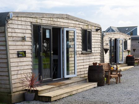 Two wooden lodges with steps and patio furniture outside at Wheal Amelia Lodge in Wendron near Helston