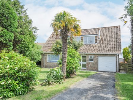 A brick house with a tiled roof a driveway and a garage surrounded by trees and bushes at Sea Drift in Carlyon Bay near Charlestown
