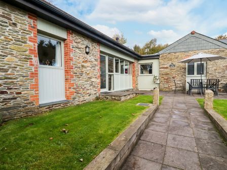 An outdoor area with a stone building and seating at The Stables Davidstow near Camelford