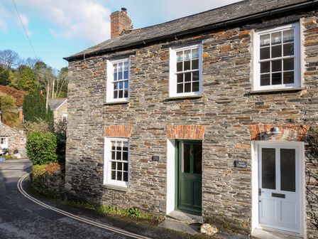 Stone cottage with green and white doors and four windows on a street at Lowen Cottage in Boscastle