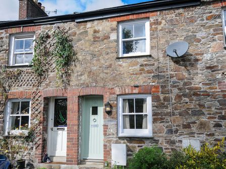 A stone cottage facade with two doors two windows and a satellite dish at 15 The Moors in Lostwithiel