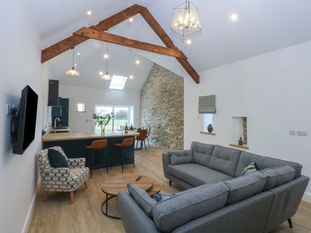 A living room with a couch and kitchen island at Beudy