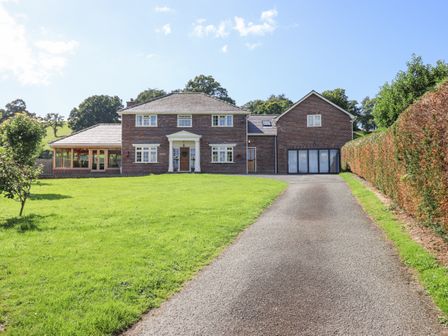 A driveway leading to a two-story brick house with a lawn and hedges at Talar Wen in Bala