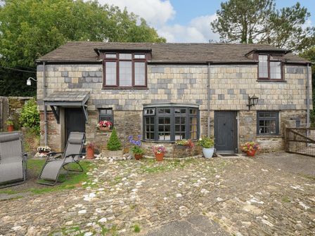 Stone cottage with multiple windows and doors flower pots on a stone driveway at Manor Cottage Barn Stoke Climsland near Callington