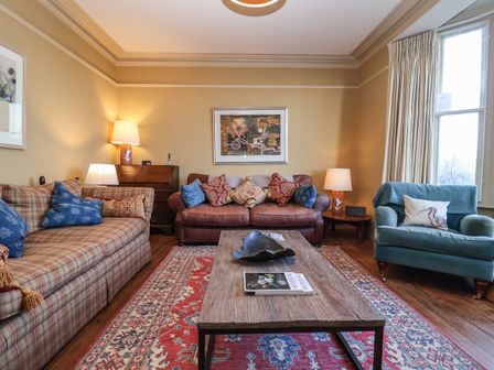 A living room with sofas and armchair around a wooden coffee table at 11a Market Cross Place in Aldeburgh