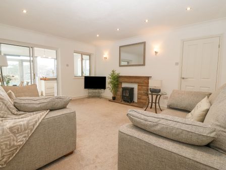A living room with two sofas a TV a fireplace and a glass table lamp at Riverview Apartment in Cemaes Bay