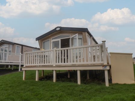 A mobile home with a white deck on a grassy area at 47 The Drake Forgetmeknot in Cayton Bay