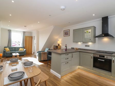 An open plan kitchen and living area with dining table and chairs at 2 South Street in Fletchertown near Aspatria