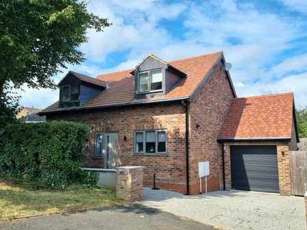 A brick house with two dormer windows a front door and a garage at Martindale Cottage in Sleights