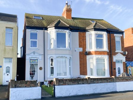 A semi detached house with a front garden and white painted walls at 46 The Promenade in Withernsea