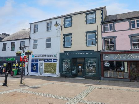 Street view of shopfronts including Londis, Llanrwst Town Council, Maid in North Wales, and La Barra cafe in Llanrwst