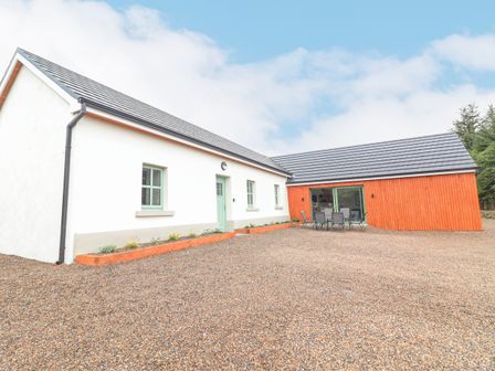 A house with white and orange exterior walls a green door and patio furniture outside at Curhoor Near Loughrea County Galway