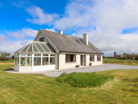 A house with a glass conservatory and a pitched roof surrounded by grass at Tonakilla House Tonakilly near Camp County Kerry
