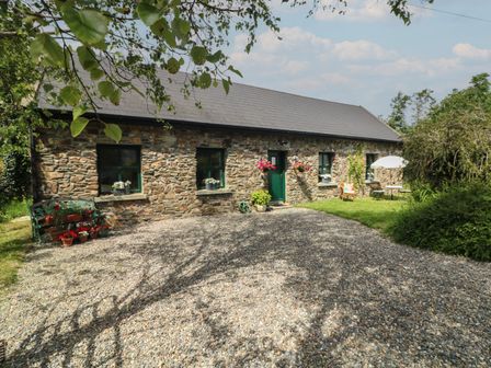 A stone house with green doors and windows surrounded by gravel and garden at Bohan Bo in Tinteskin near Kilmuckridge County Wexford
