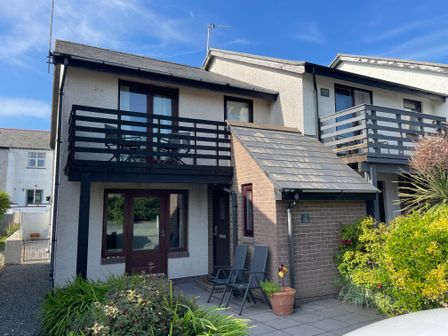 A two-story house with balconies chairs and plants in front at Ty Haf in Trearddur Bay