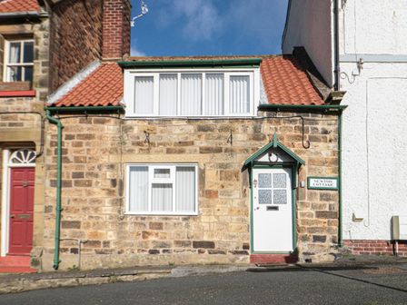 A stone cottage with a white door and windows and a red tiled roof at Newton Cottage in Fylingthorpe
