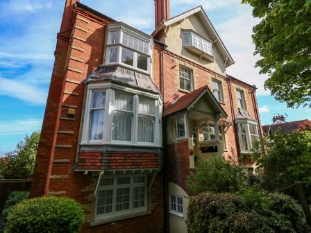 A multi-story brick house with bay windows and greenery in front at The Lobster Pot in Weymouth