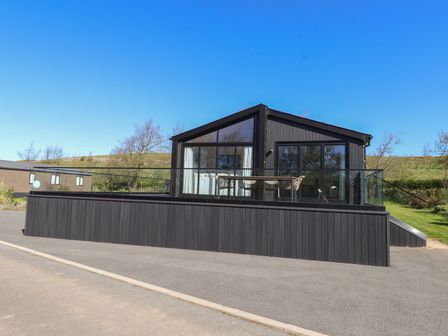 A house with a deck and glass railing at Encil Gyfrinfa in Gwynus, near Llithfaen