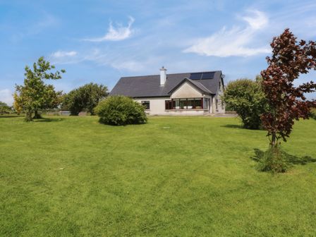 A house with a pitched roof and solar panels on a large grassy lawn with trees at Bunny Lane in Cloonflynn near Ballycarra County Mayo