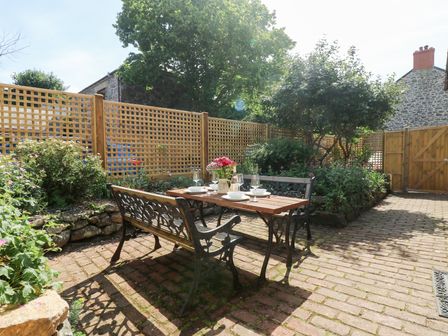 A garden with a table and chairs surrounded by plants at Bert's Barn, Mullion