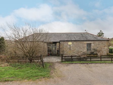 A stone building with a slate roof a tree in front and a gravel driveway at Brimpts Barn Dartmeet near Princetown